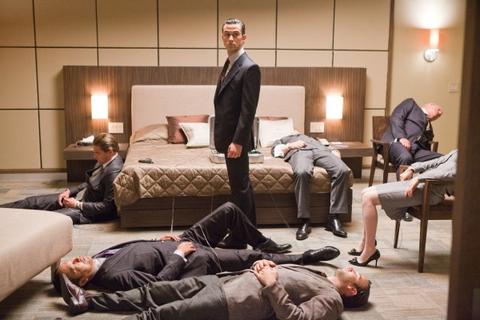 Inception. Plot summary and story structure. Arthur stands in a hotel room while all the other members of his group are laid about the room asleep in a shared dream.